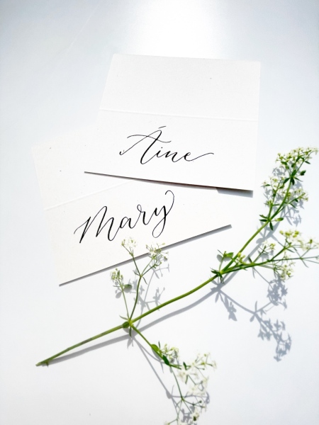 White place cards with black calligraphy and white flowers
